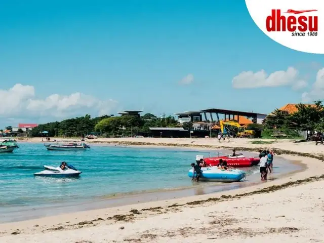 Boats and jet skis lined up on a bright Bali beach under a clear sky