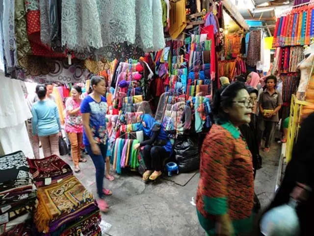 Busy local market stalls hung with clothes and everyday goods