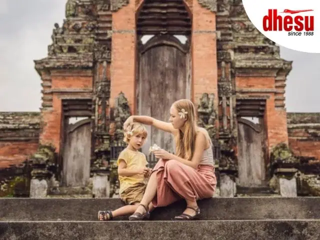 A parent and small child sitting together in a stone temple gateway