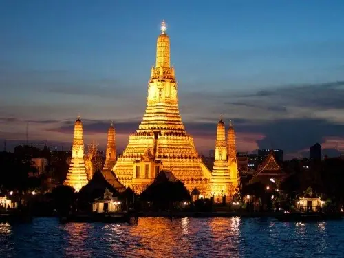 Riverside temple spires lit at dusk in Bangkok