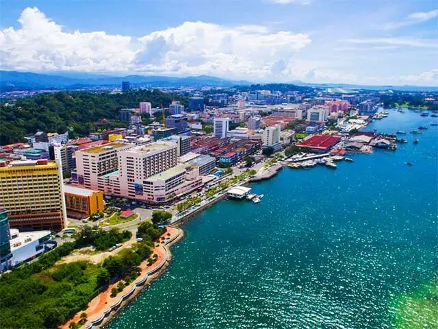 A Malaysian coastal city waterfront under a golden-hour sky