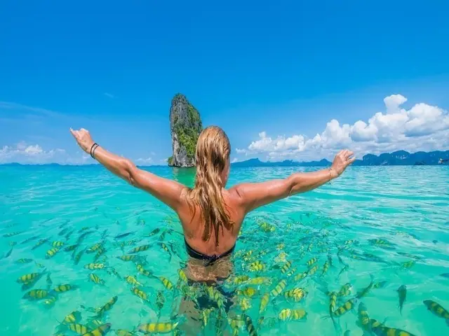 Swimmer among shoals of fish off Poda Island, Krabi