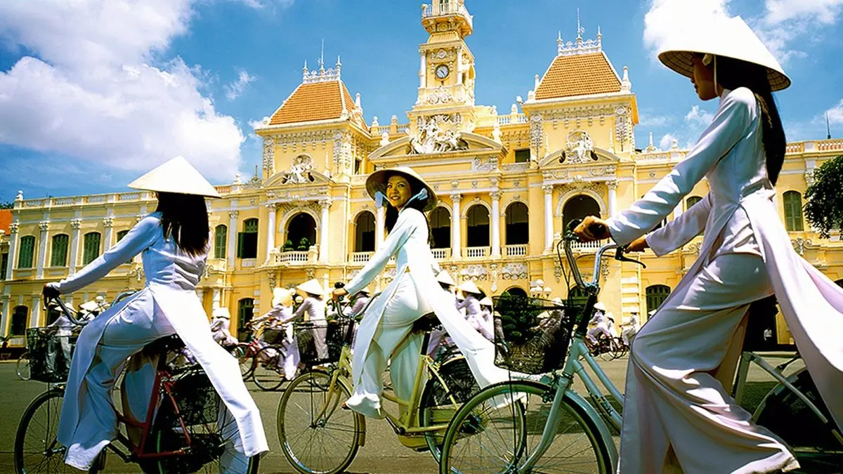 Cyclists in ao dai passing Ho Chi Minh City Hall